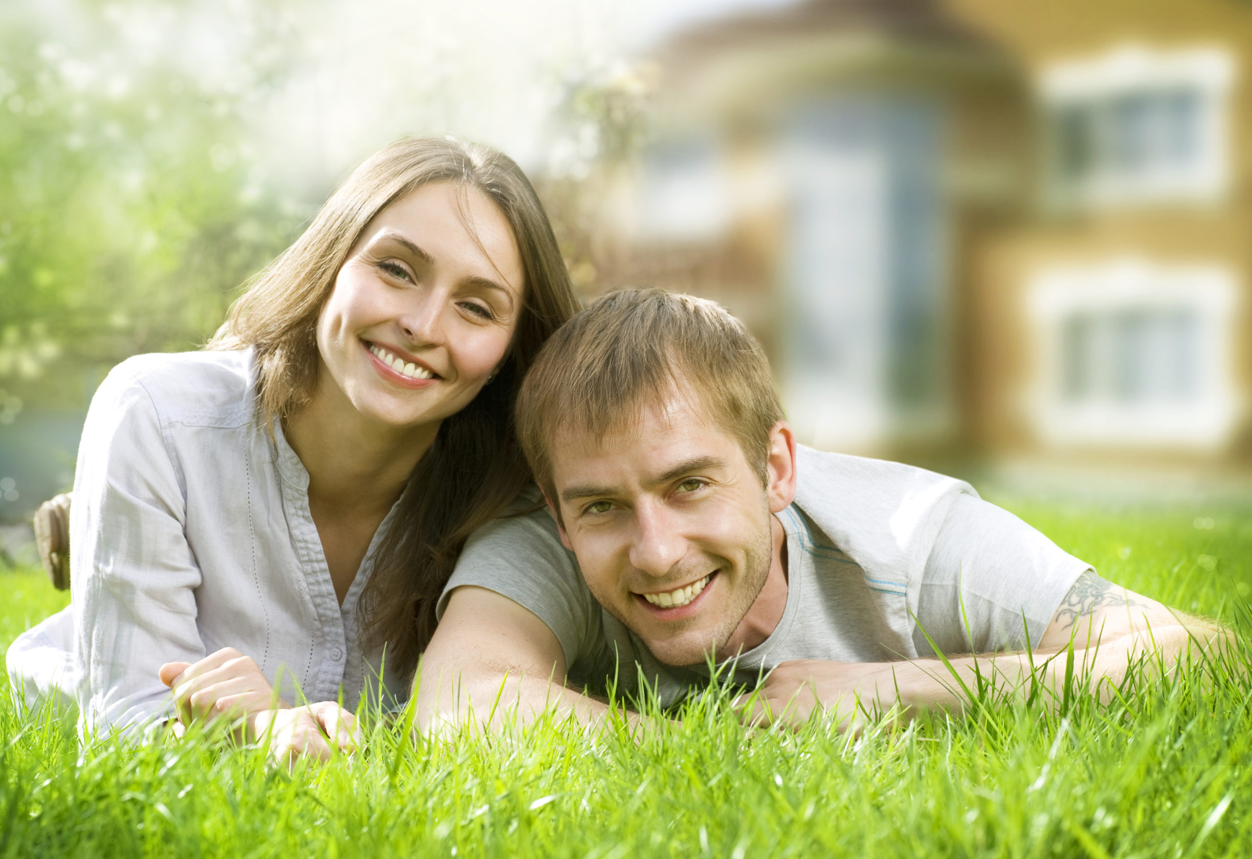 Happy Couple Near Their Home. Smiling Family Outdoor. Real Estat